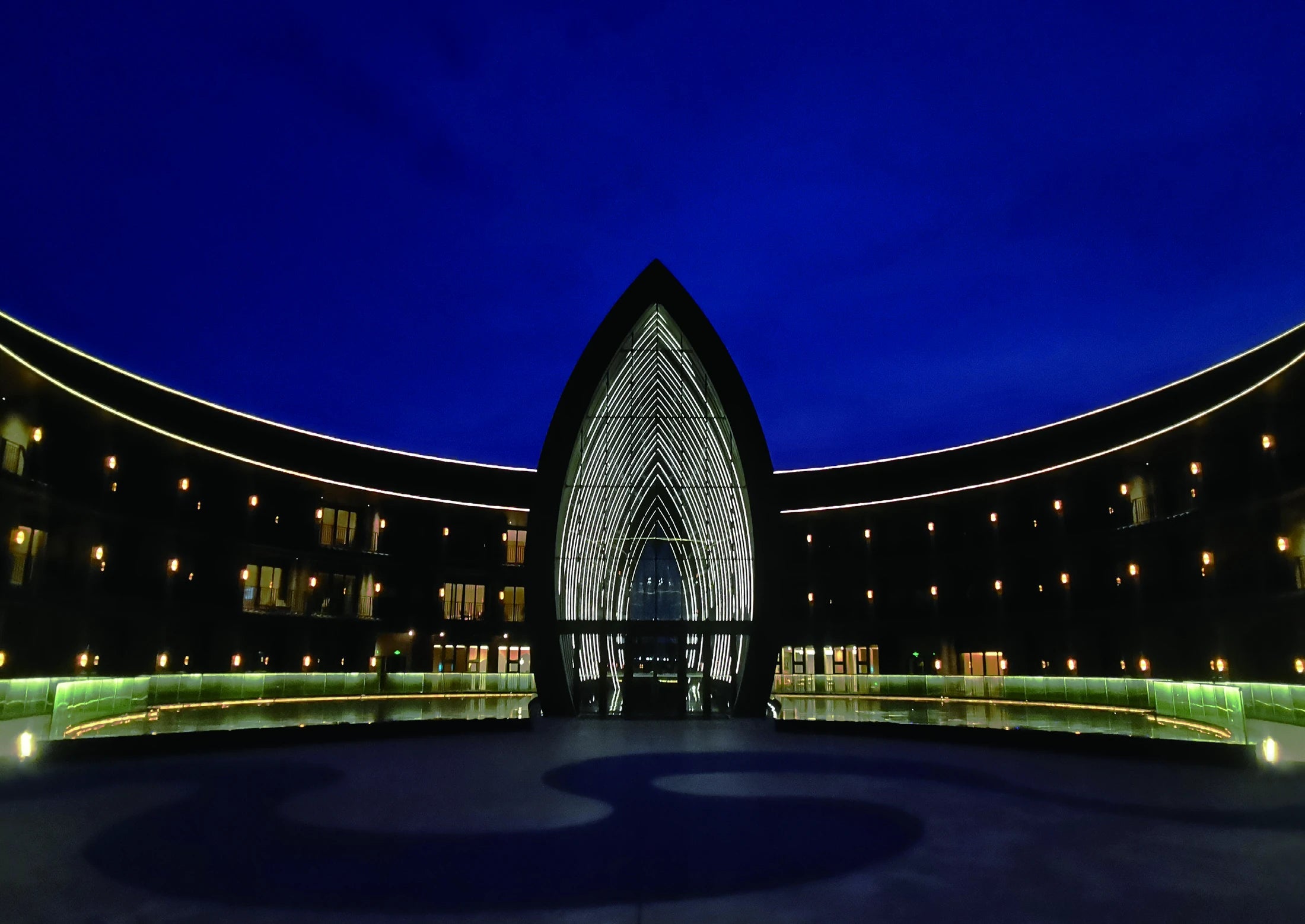 Architectural outlines and handrails illuminated around a hotel courtyard.