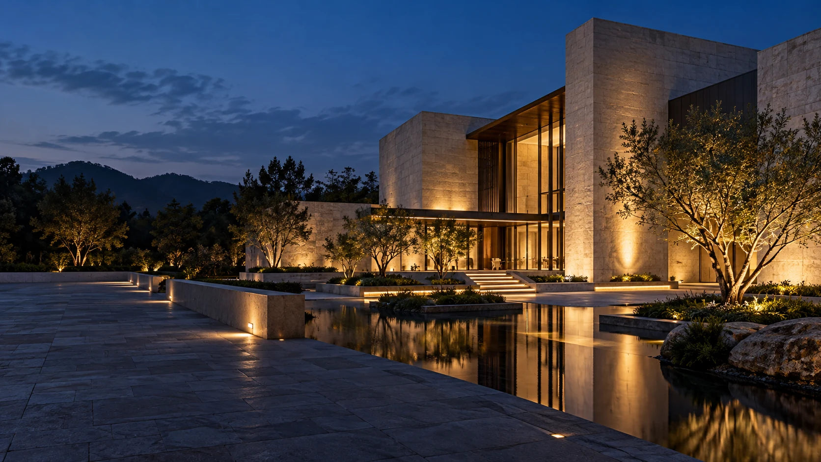 Warm architectural lighting along a stone facade and courtyard at dusk